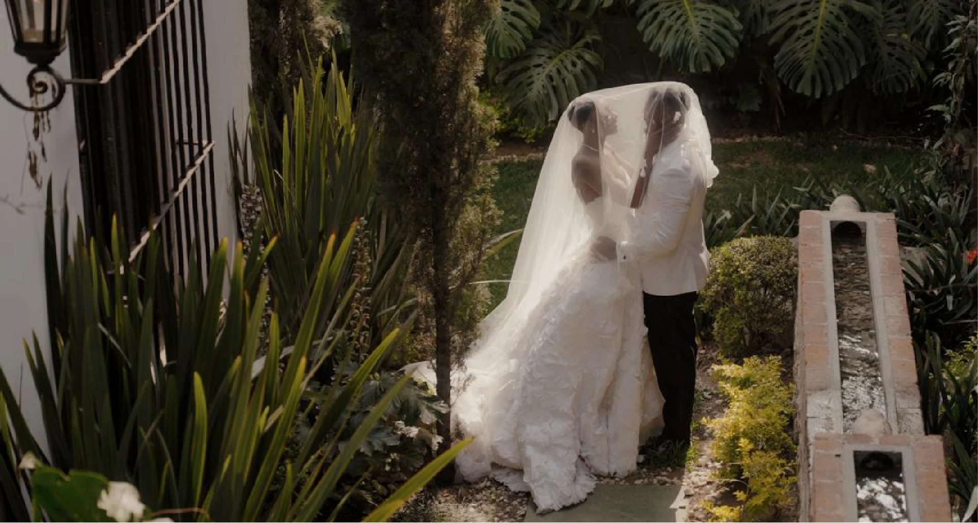Bride and groom under the veil in a tropical garden