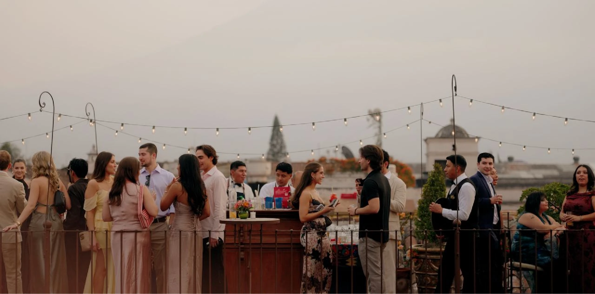Rooftop wedding reception with string lights at sunset