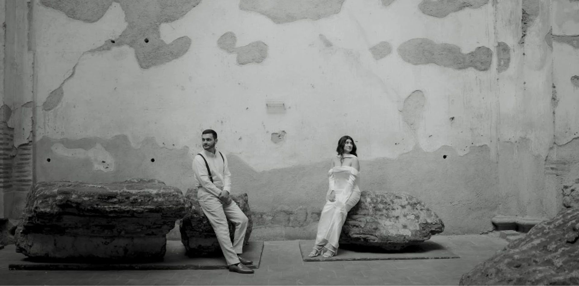 Bride and groom seated in front of a textured stone wall