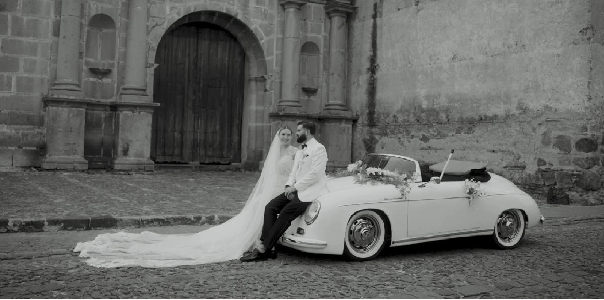Bride and groom on a classic convertible in front of a colonial church in Antigua Guatemala